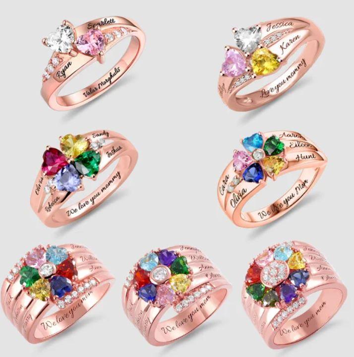 Seven rose gold rings with heart-shaped gemstones in various colors, each personalized with names and inscriptions like "We love you mommy" and "Valor morghulis."