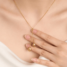 Gold Y-shaped necklace with 'Dad' and 'Mom' engraved teardrop pendants, worn by a woman touching the jewelry.