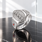 Personalized silver football ring with engraved name Kevin, red birthstone, and “I am proud of you” message on the band.