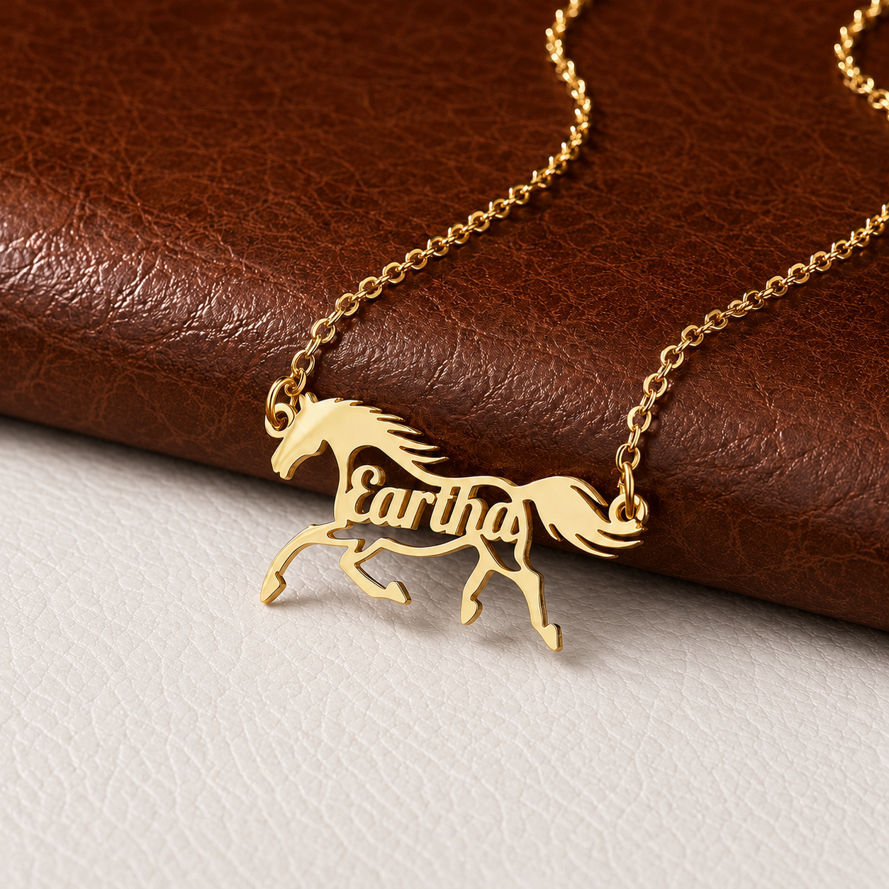 Gold custom horse name necklace displayed on brown leather