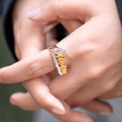 Close-up of a custom gold and silver 'Olivia' name ring in script on a woman's finger.