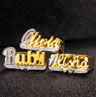 Gold and silver name rings displaying 'Olivia', 'Ruby', and 'Alisha', set against a textured black background.