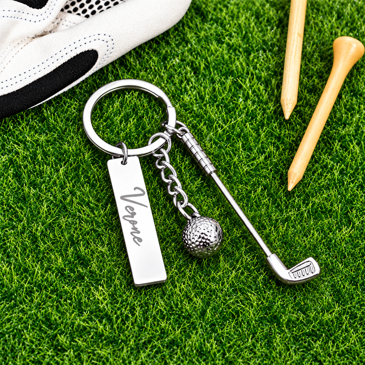 Personalized golf keychain with engraved name, golf club and ball charms beside golf glove and tees