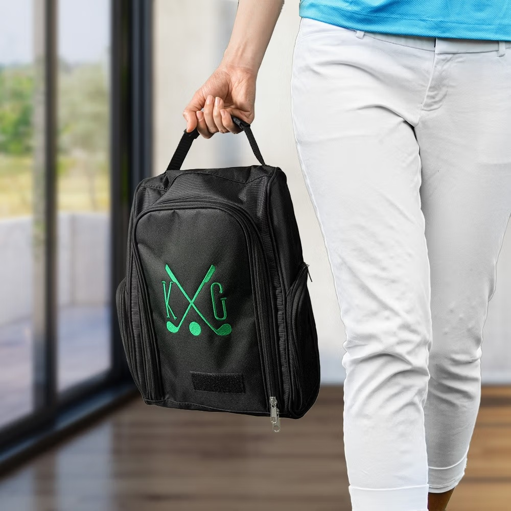 Black personalized golf shoe bag with green embroidered golf design being carried