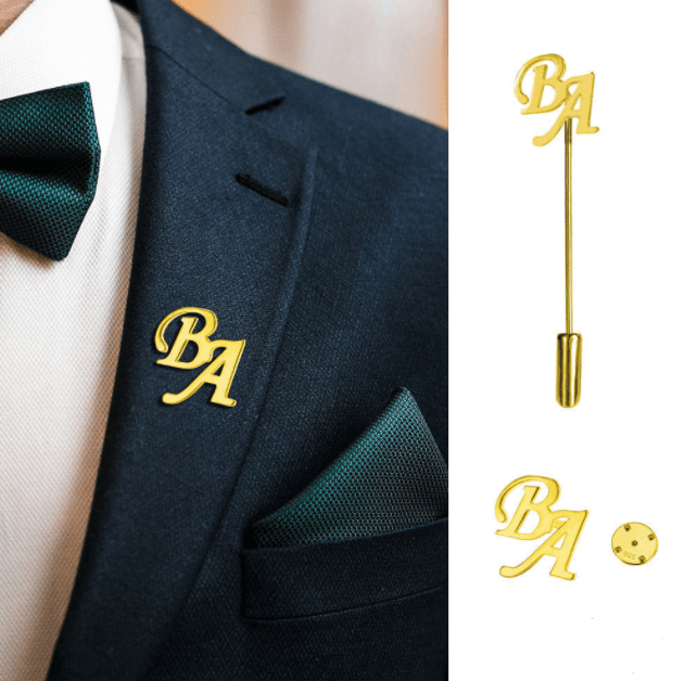 Gold custom initial lapel pins in "BA" letters displayed on a navy suit, highlighting a personalized and sophisticated touch for formal attire.