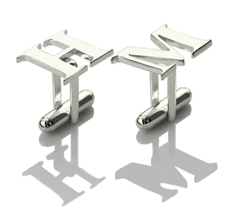 Silver initial cufflinks with the letters 'HM' on a reflective white surface casting distinct shadows.