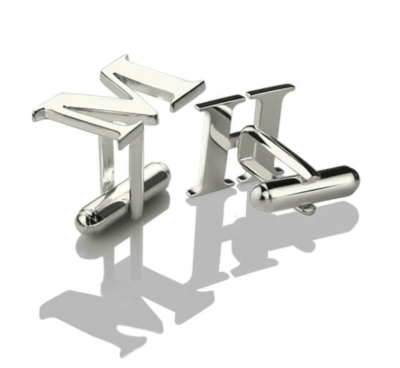 Silver initial cufflinks with the letters 'HM' on a reflective white surface, casting sharp shadows.