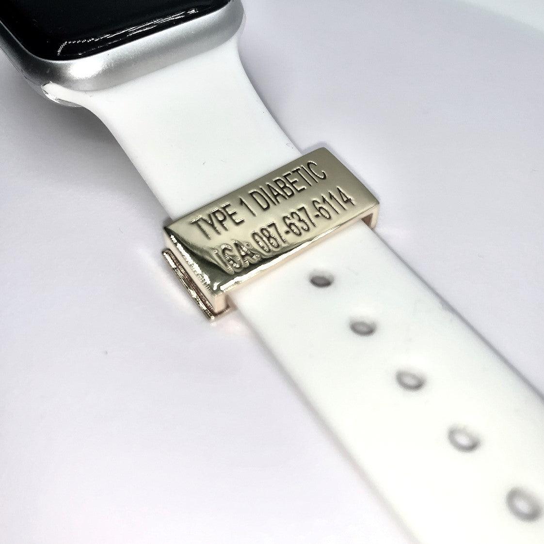 A gold medical tag attached to a white smartwatch band with the inscription "TYPE 1 DIABETIC ICA: 087-637-6114" displayed on a white background.