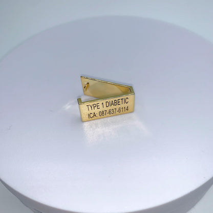 A gold medical tag with the inscription "TYPE 1 DIABETIC ICA: 087-637-6114" displayed on a white background.