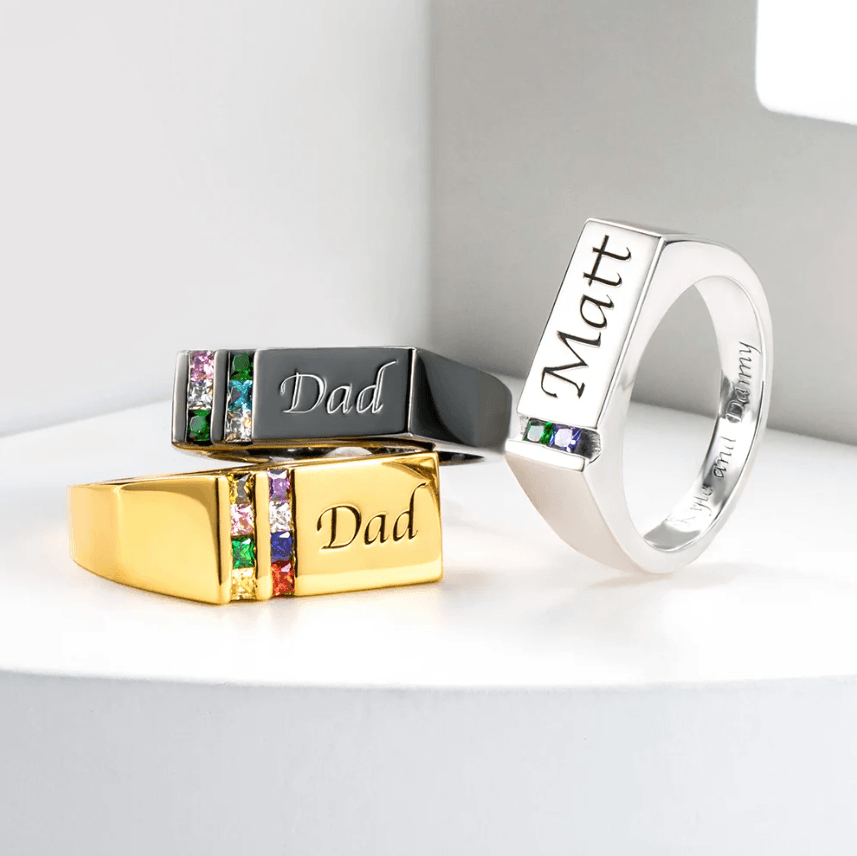 Custom men's rings in silver, gold, and black, featuring birthstones and engravings with 'Dad' and 'Matt' personalized options.