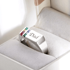 Silver 'Dad' engraved ring with multicolored birthstones displayed in a plush jewelry box.