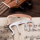 Customized music book holder clips on sheet music with a ukulele in the background.