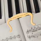 Golden music book clip with 'when words fade, music speaks' on piano keys and sheet music.