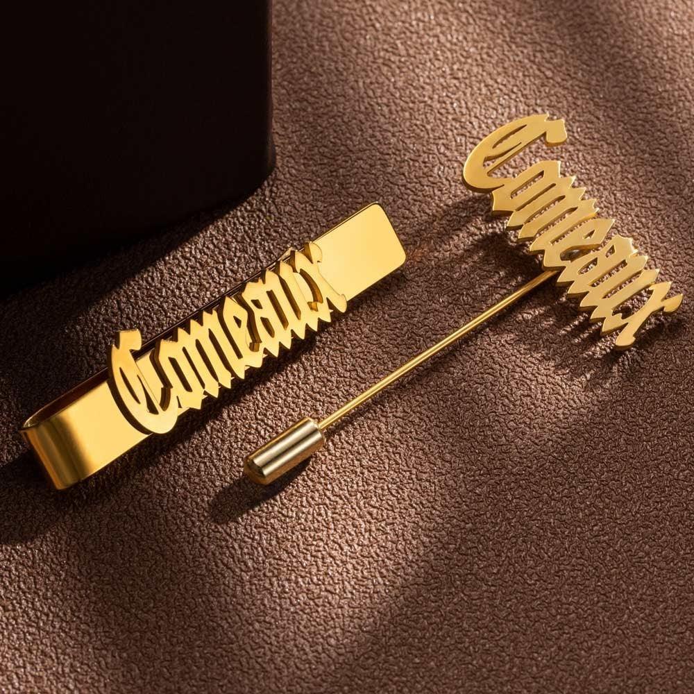 Gold tie bar and lapel pin with the word "Comedian" in cursive, against a textured brown background.