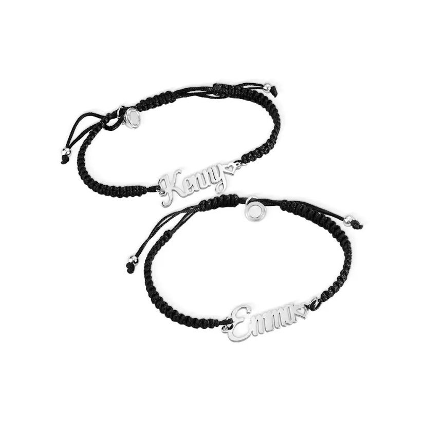 Two black cord bracelets with silver nameplates reading "Kenny" and "Emma." Each bracelet has silver ends and a small white and silver circular bead where the bracelet joins.