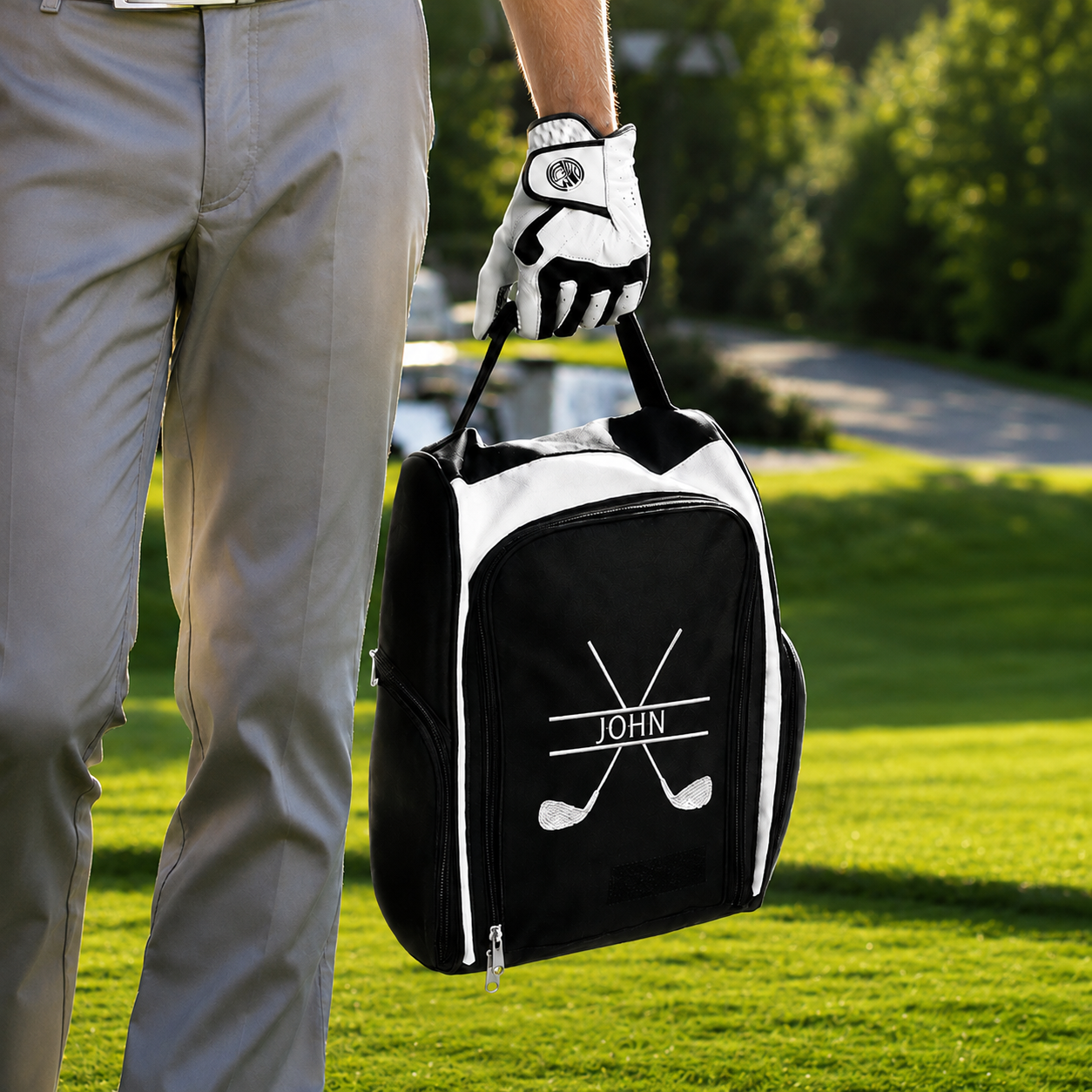 Personalized golf shoe bag with white JOHN embroidery carried by golfer on golf course
