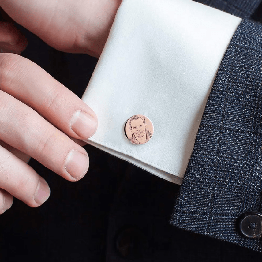 Man adjusting a custom cufflink with engraved portrait on his shirt sleeve.