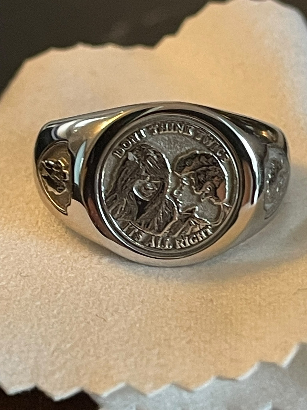 Personalised silver-tone signet ring with engraved couple portrait, circular lettering and decorative side details.