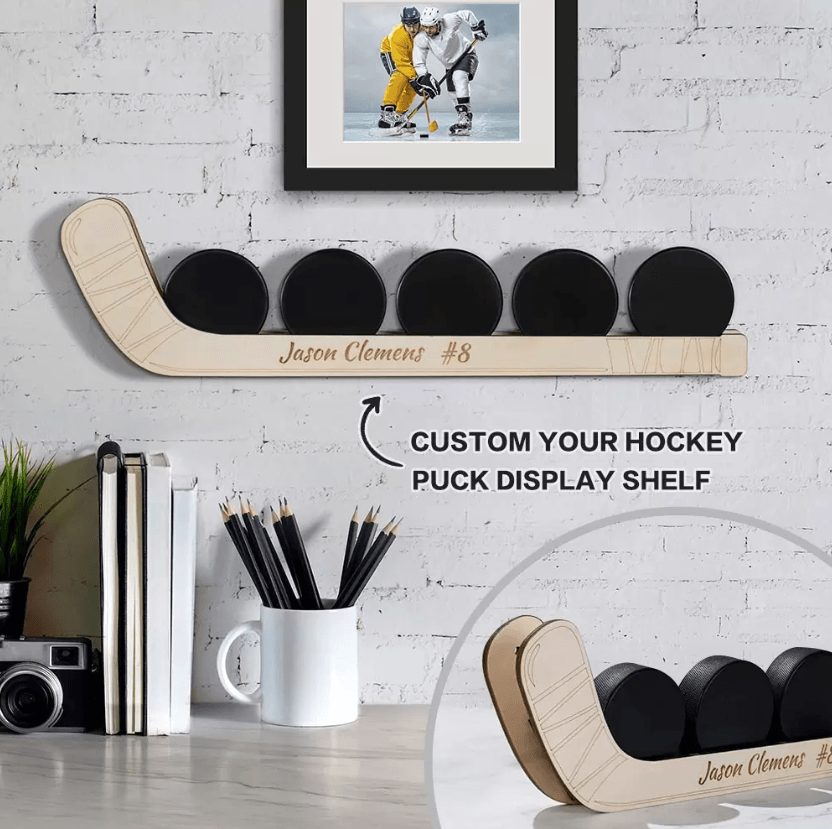 Customizable wooden hockey puck display shelf with five pucks, personalized with the name "Jason Clemens #8", shown mounted on a wall and placed on a table.