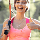 Smiling female tennis player wearing a personalized silver tennis racket necklace with a heart charm, holding a tennis racket and giving a thumbs up.