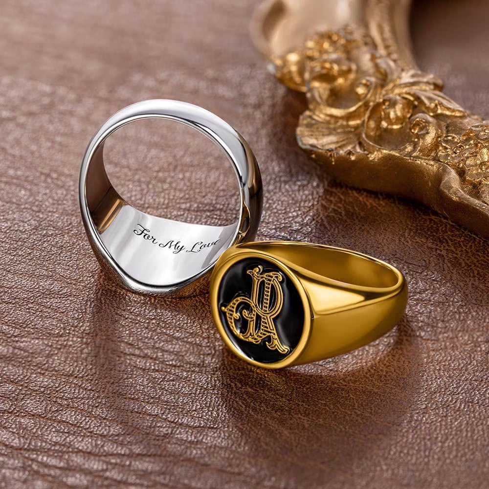 Gold tone double initials signet ring shown from the front beside the polished ring band.