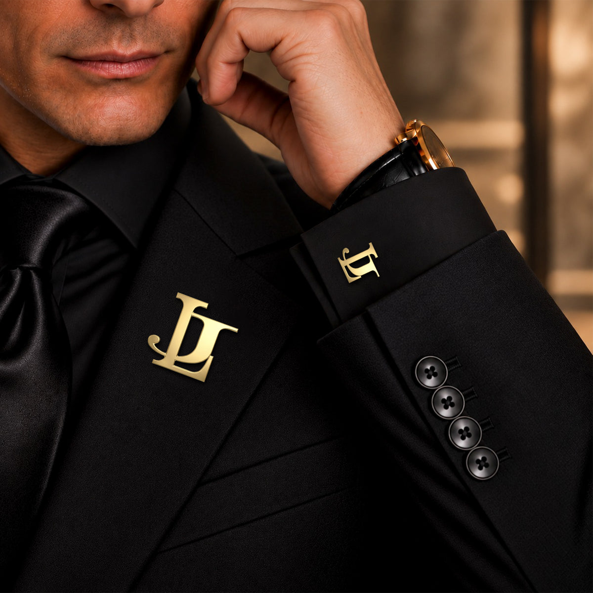 Personalized gold entwined two initials lapel pin and matching cufflink worn with a black formal suit.
