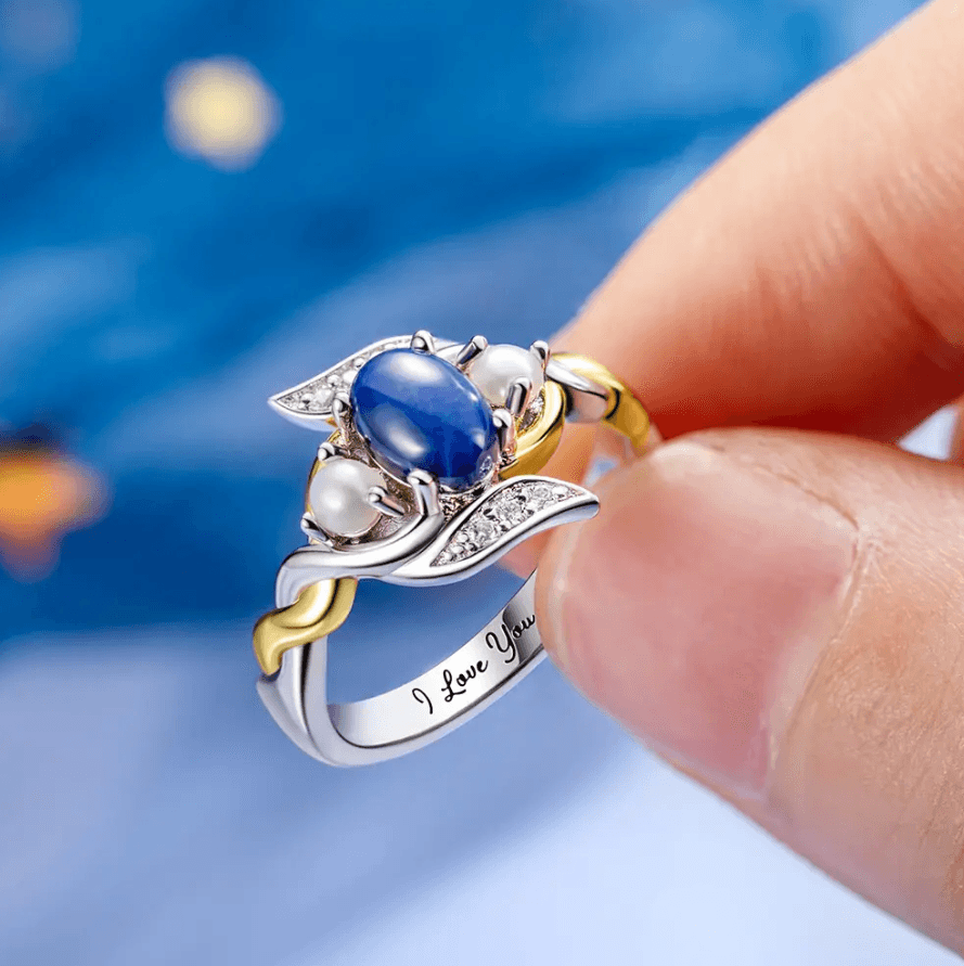 A close-up of a Blue Star Sapphire and Pearl ring, featuring Sterling Silver with 18K Gold Plating and engraved with "I Love You"