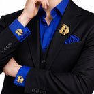 Gold interlocking initials cufflinks and matching lapel pin set worn with a black suit and royal blue shirt
