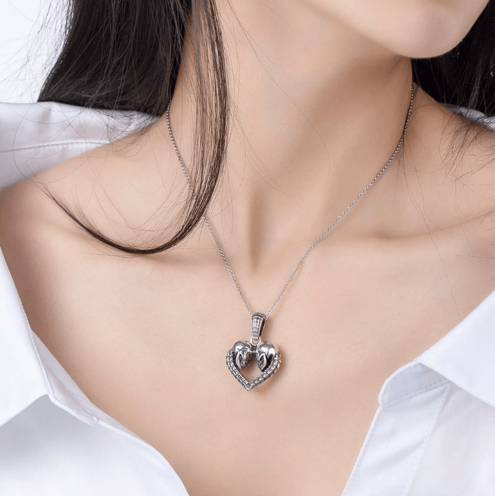 Elegant skull heart necklace worn by a woman in a white blouse, subtle yet striking.