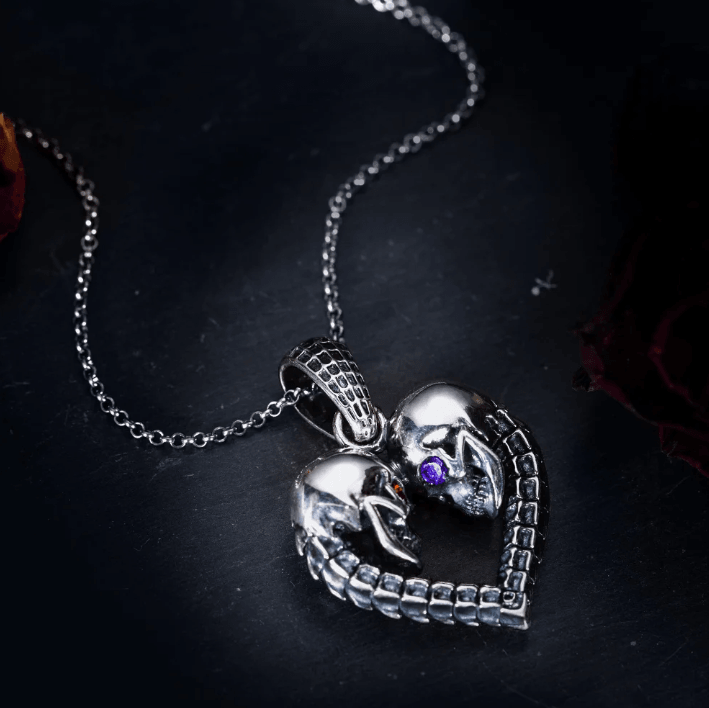 Stylish silver heart pendant with skull design and purple gemstone on dark background.