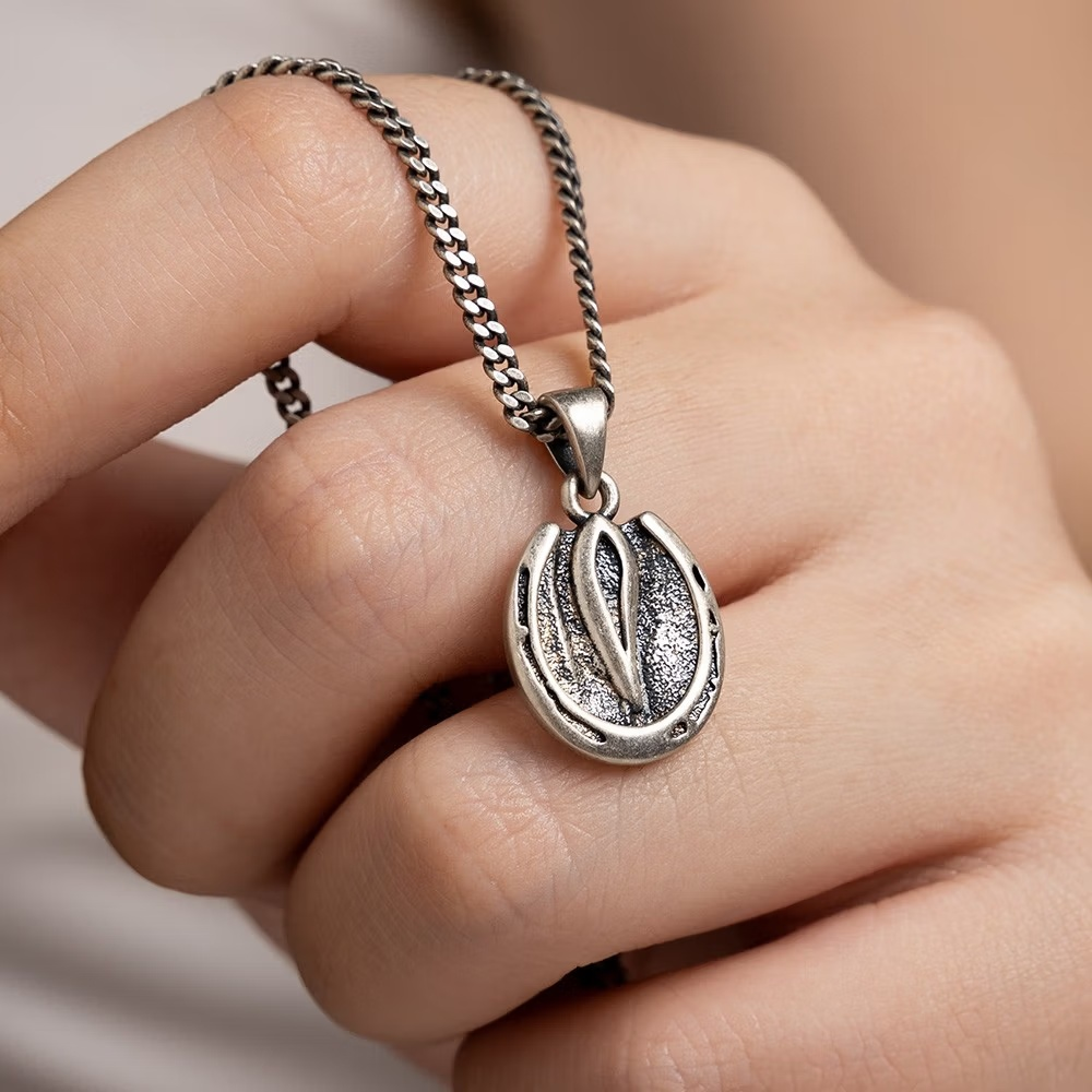 Silver horse hoof pendant necklace held in hand showing pendant size
