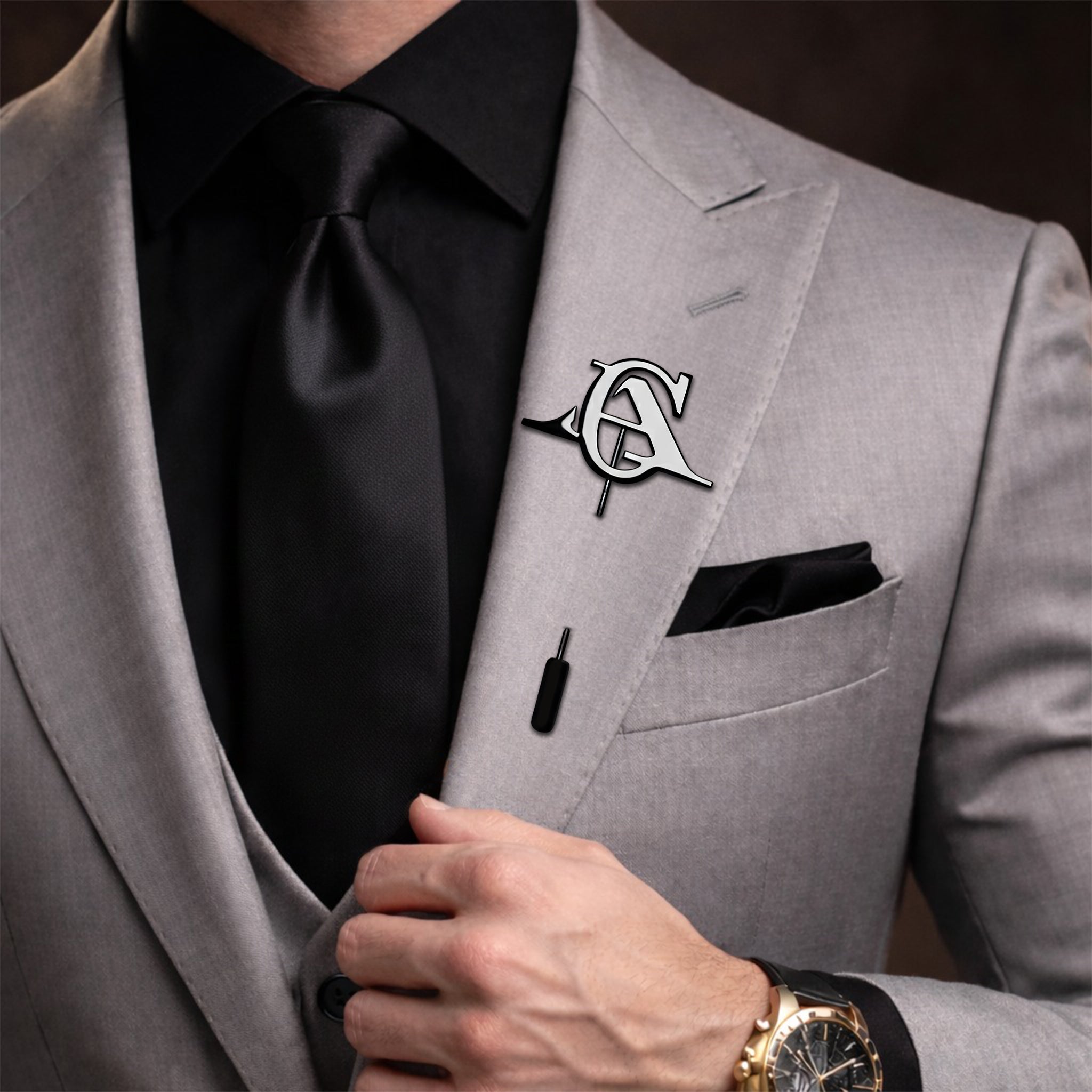 Personalized black intertwined initials lapel pin worn on a grey suit