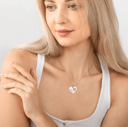 Blonde woman wearing a silver heart necklace with 'Mama' engraving, showcasing the elegant and personalized jewelry design against a white top.