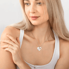 Blonde woman wearing a silver heart necklace with 'Mama' engraving, showcasing the elegant and personalized jewelry design against a white top.