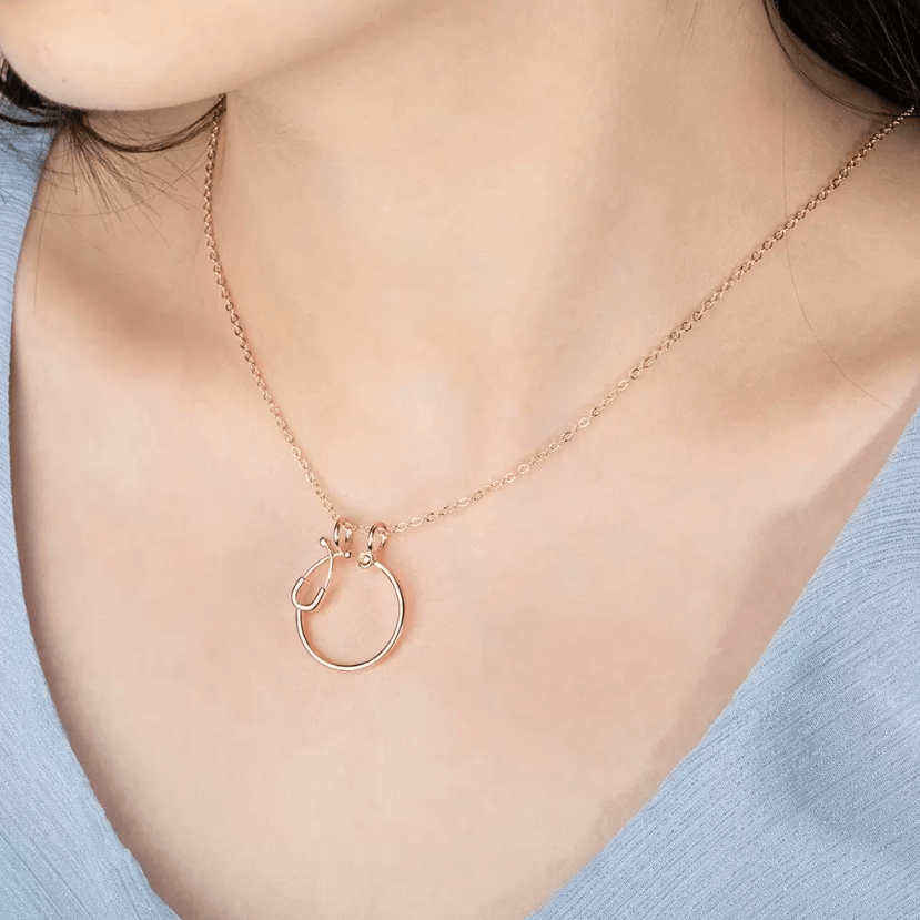 Woman wearing a rose gold ring holder necklace with a stethoscope design, perfect for medical professionals, featuring a customizable birthstone.