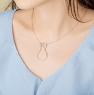 Woman wearing a silver ring holder necklace with a stethoscope design, perfect for medical professionals, featuring a customizable birthstone.