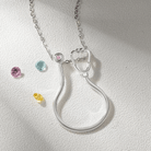 Silver ring holder necklace with a stethoscope design, customizable with birthstones. Perfect for medical professionals. Includes pink, blue, and yellow gemstones.