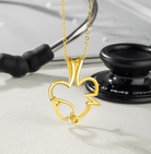 Gold ring holder necklace with a heart and EKG design, featuring a customizable birthstone. Perfect for medical professionals. Background includes a stethoscope.