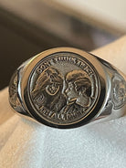 Side-angle view of a bespoke portrait signet ring with detailed couple engraving and decorative shield emblem.