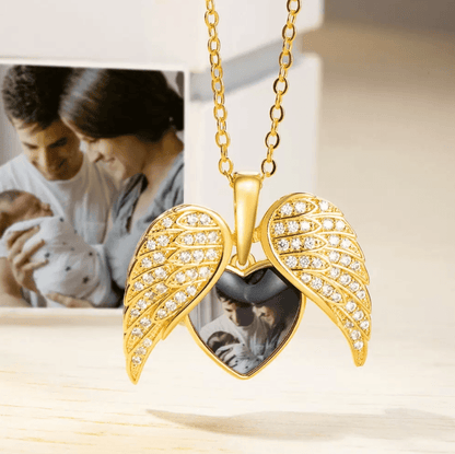 Gold angel wings necklace with heart-shaped locket and photo pendant, adorned with rhinestones.