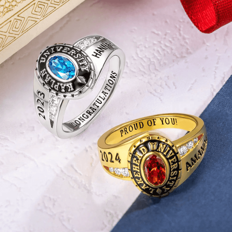Custom sterling silver class rings with blue and red stones, engraved with school names and graduation years.