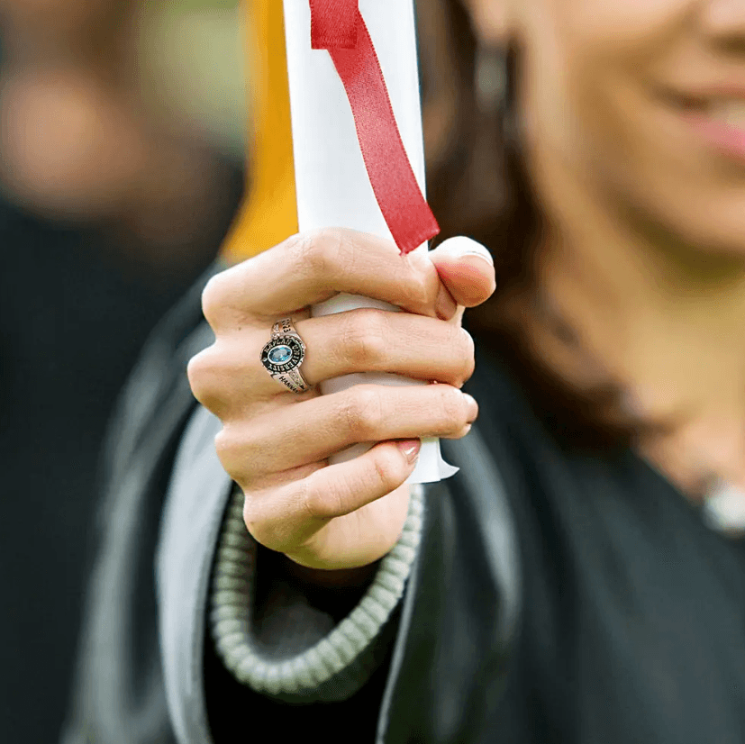 Graduate holding a diploma, wearing a sterling silver class ring with a blue stone.