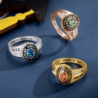 Assortment of custom class rings in gold and silver with personalized engravings and colored stones.