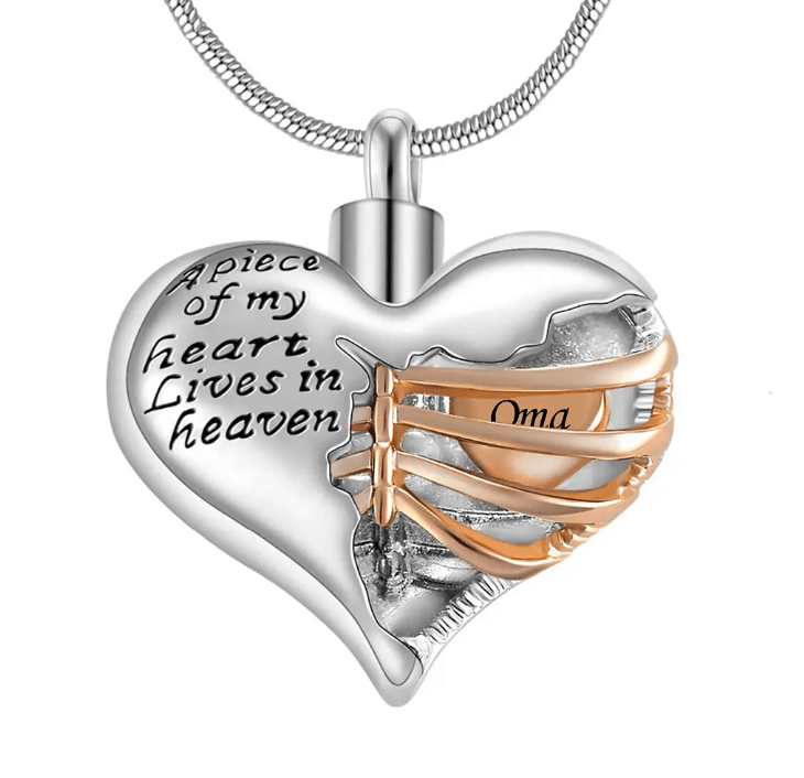 A heart-shaped pendant with the inscription "A piece of my heart lives in heaven," featuring a gold ribbon with the word "Oma."