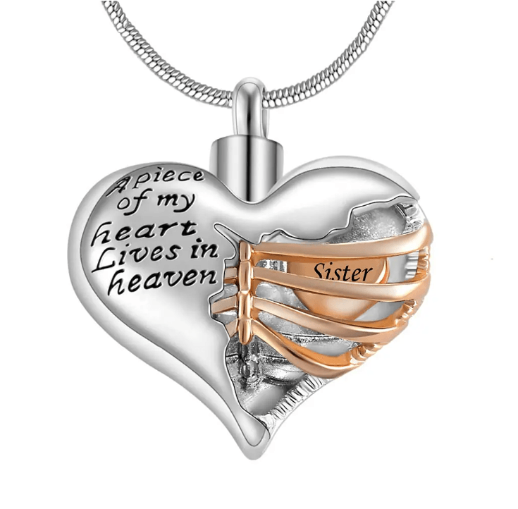 A heart-shaped pendant with the inscription "A piece of my heart lives in heaven," featuring a gold ribbon with the word "Sister."