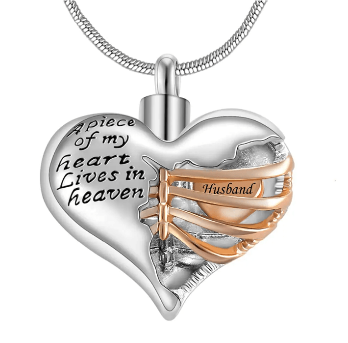 A heart-shaped pendant with the inscription "A piece of my heart lives in heaven," featuring a gold ribbon with the word "Husband."