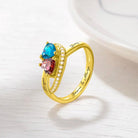 Gold ring with blue and red heart-shaped gems and "Bryan & Jenny Forever & Always" inscription.