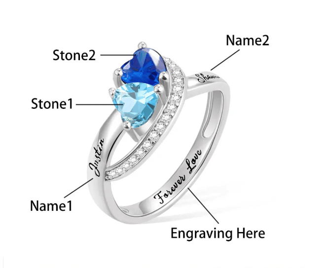 Personalized double heart birthstone ring with custom engravings. Features two heart-shaped stones, personalized names, and an additional engraved message.