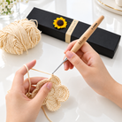 Personalized crochet hook set being used with engraved wooden handle and sunflower gift box