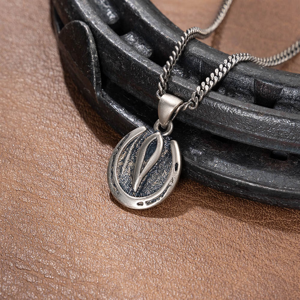 Silver horse hoof pendant necklace displayed with antique horseshoe